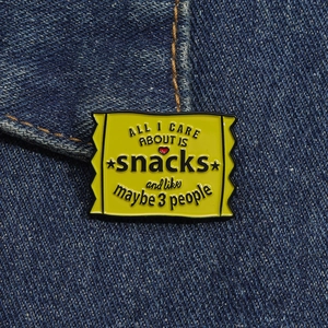 Macro detail of yellow enamel snack bag brooch pinned on dark blue denim fabric