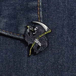 Close-up of Grim Reaper enamel pin with scythe on denim background texture