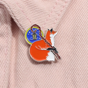 Detail of cute fox enamel pin with lantern attached to a pink fabric collar