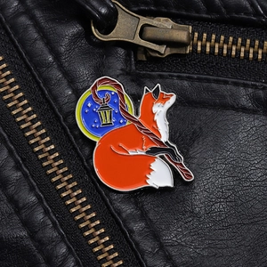Detail showing a cartoon fox enamel pin with a golden lantern on black leather