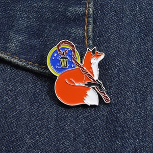 Close-up of a red fox enamel brooch with a lantern scepter on dark denim fabric