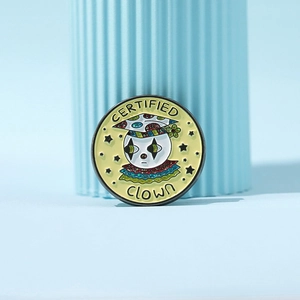Macro shot of yellow enamel clown badge with black stars and shiny glitter details