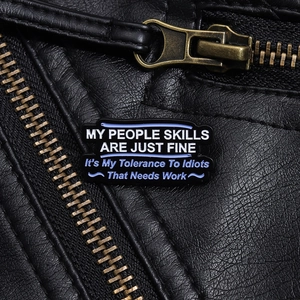 Detail of creative text enamel pin on black leather jacket with punk style text