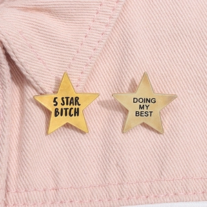 Close-up of star-shaped metal badges with text on pink denim fabric material