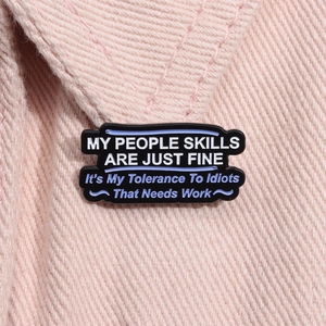 Detail of funny quote enamel pin on pink fabric showing metal edges and lettering