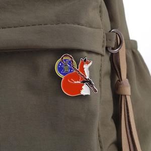 Detailed view of fox enamel pin with magic wand on olive green fabric bag background