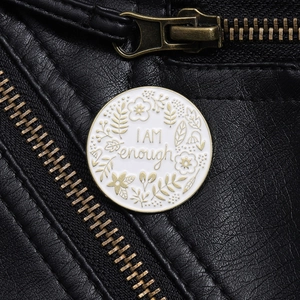 Detailed macro view of an enamel pin with I AM enough quote on black leather jacket