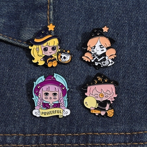 Set of four colorful cartoon witch enamel pins displayed on blue denim fabric background