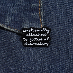 Makroaufnahme der schwarzen Emaille-Anstecknadel mit Text emotionally attached to fictional characters