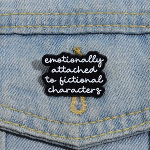 Detail einer Emaille-Brosche mit Fiktional-Charakter-Text auf blauer Jeansjacke