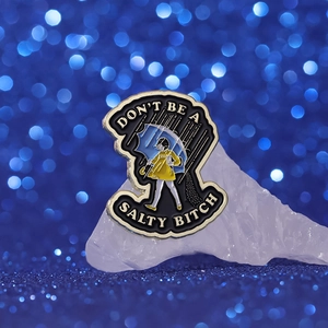 Detail of creative girl in yellow raincoat enamel pin with Don't Be A Salty Bitch text