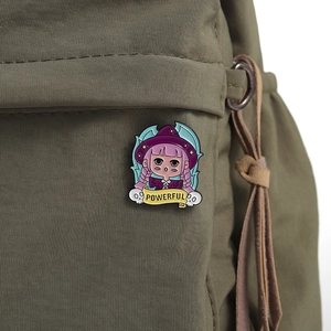 Detail of magic girl enamel pin with powerful banner on a green canvas backpack