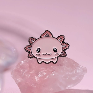 Macro shot of cute pink axolotl enamel pin on crystal stone showing glossy finish and details