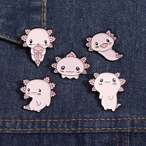 Set of five cute pink axolotl enamel pins displayed on dark blue denim fabric