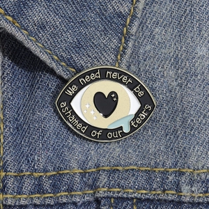 Détail d'une broche en émail en forme d'œil avec larmes sur tissu denim bleu