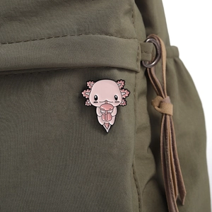 Close-up of cute pink axolotl enamel pin with boba tea on a green nylon bag