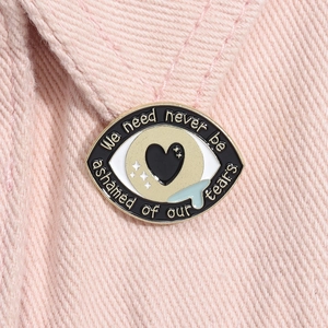Vue rapprochée de la broche œil en émail avec larme bleue sur denim rose