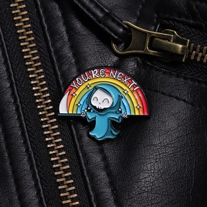 Dettaglio della spilla smaltata con la mietitrice e arcobaleno YOU'RE NEXT su pelle nera