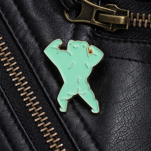 Macro detail of cute muscular frog enamel pin on black leather jacket with gold trim