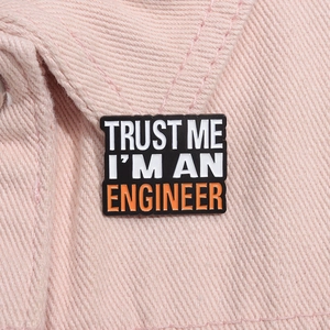Detailed close-up of rectangular enamel pin with Trust Me I'm An Engineer text on denim