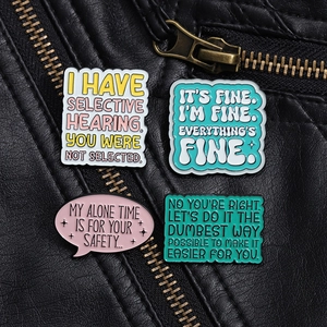 Détail de quatre broches colorées en émail avec citations sur cuir noir texturé