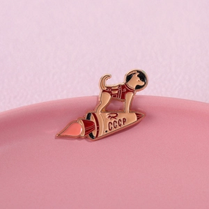 Detailed close-up of Laika space dog enamel pin featuring CCCP rocket and shuttle design