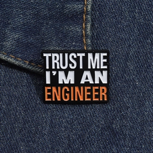 Close-up of Trust Me I'm An Engineer enamel pin on a blue denim jacket fabric