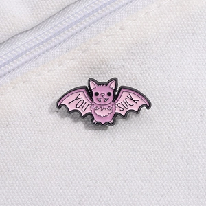 Detail of pink bat enamel pin with You Suck text on white canvas background