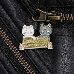Dettaglio ravvicinato di una spilla smaltata con gatto ouija su giacca di pelle