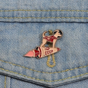 Retro Soviet CCCP space dog and rocket enamel pin badge on blue denim fabric
