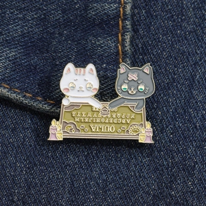 Dettaglio ravvicinato della spilla smaltata con gatto e Ouija su tessuto denim blu