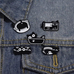 Lot de cinq broches chat noir en métal sur fond de tissu en denim bleu robuste