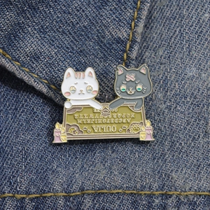 Dettaglio della spilla smaltata gatto Ouija esposta su tessuto denim blu classico