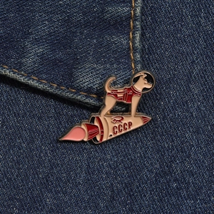 Detail of CCCP space dog enamel pin featuring Laika on a rocket over denim fabric