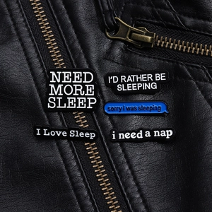 Set of five punk-style enamel pins with sleep phrases on a black leather jacket