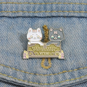Dettaglio di spilla in smalto a forma di gatto con tavola Ouija su denim blu