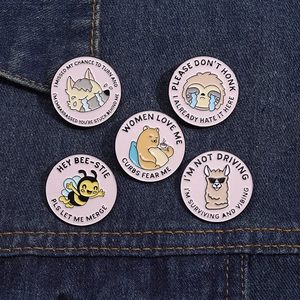 Detailed view of 5-piece set of pink round animal enamel pins on denim fabric backdrop