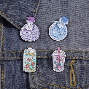 Détail de quatre pins en émail thème espace avec fantômes et étoiles sur denim bleu