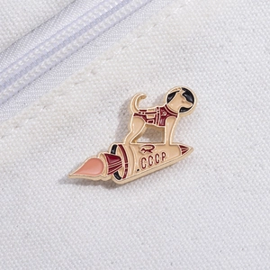 Detail of enamel pin featuring Laika the space dog and a Soviet rocket on white canvas