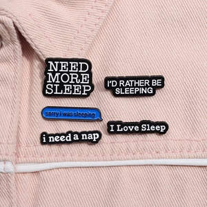 Detailed close-up of sleep themed enamel pins on pink denim fabric showing fine texture