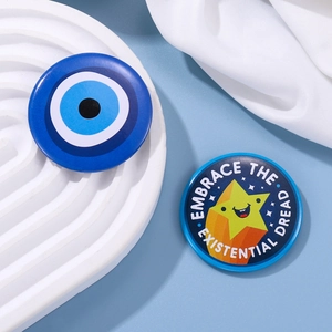Detailed view of Evil Eye and Starry Face tinplate pins on a white decorative wave tray