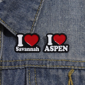 Detailansicht der schwarzen Emaille-Pins mit den Schriftzügen I Love Savannah und ASPEN