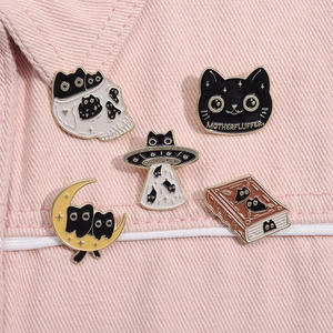 Set of five cat-themed enamel pins featuring UFO and skull designs on pink denim fabric