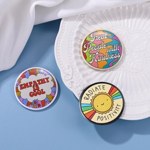 Close-up of colorful round tinplate badges with motivational English quotes on a ceramic plate