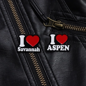 Nahaufnahme von Savannah und Aspen Emaille-Pins mit roten Herzen auf schwarzer Lederjacke