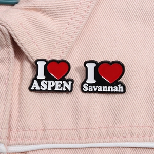 Set aus Emaille-Pins mit I Love Aspen und Savannah Motiven auf pinker Jeansjacke-Oberfläche