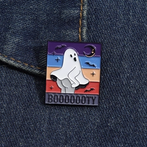 Détail du pin's émaillé fantôme avec texte BOOOOOOTY sur tissu en denim bleu foncé