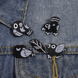 Five-piece black and white cartoon crow and feather enamel pin set on blue denim fabric