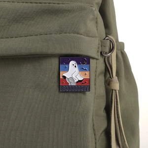 Gros plan d'un badge émaillé fantôme d'Halloween avec texte BOOOOOOTY sur un sac