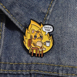 Detailed close-up of cartoon cat enamel pin with This Is Fine text on denim fabric
